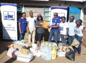 Joseph Waithaka, Head of Diaspora Banking (center) presents food stuffs to Eunice Menja (3rd left), the founder of the Upendo Children's home as ABC Bank staff look on.